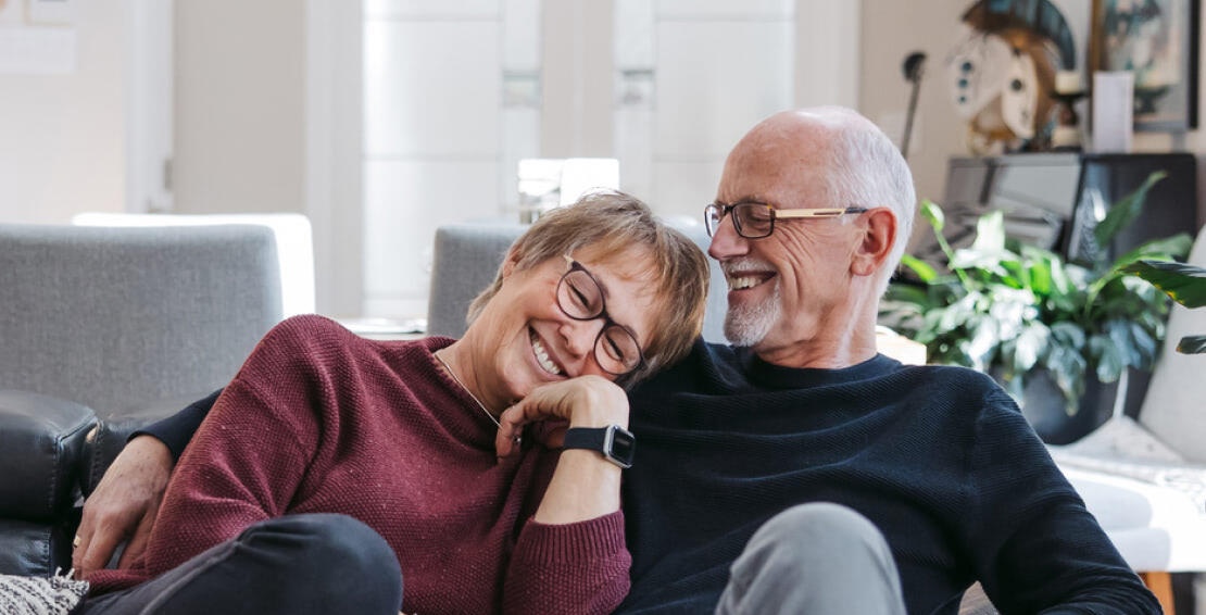 Older couple laughing together on a couch at home