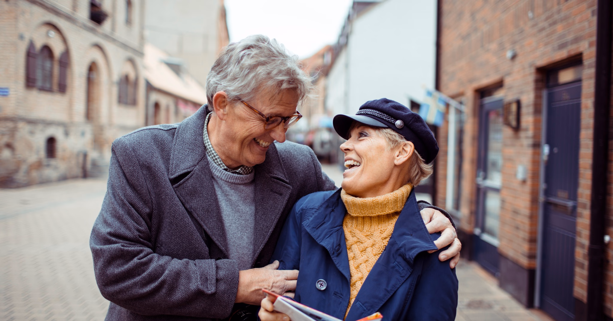 Older couple smiling at each other on a city sidewalk